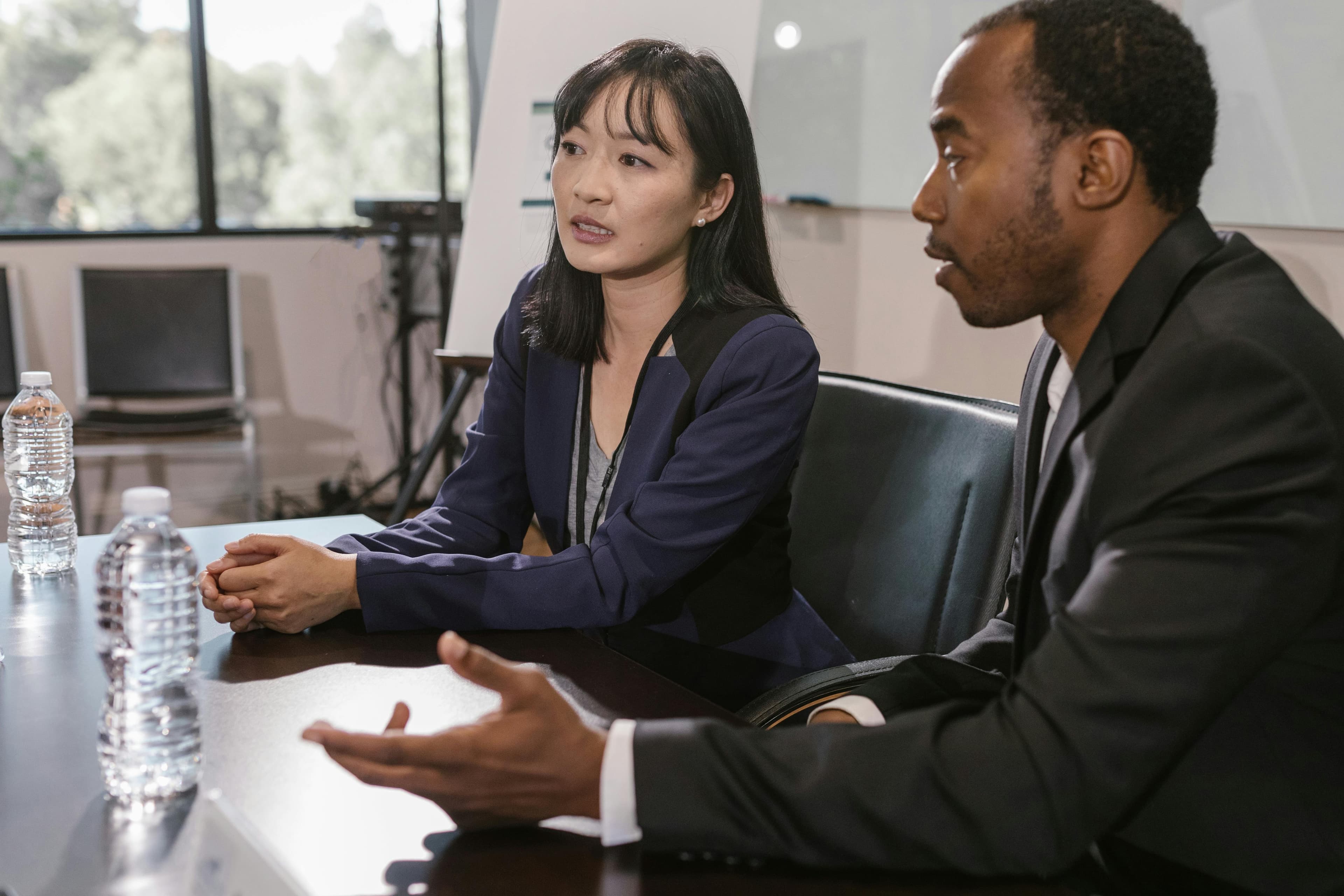 Diverse group of business professionals shaking hands in a modern corporate boardroom with glass walls, atmosphere